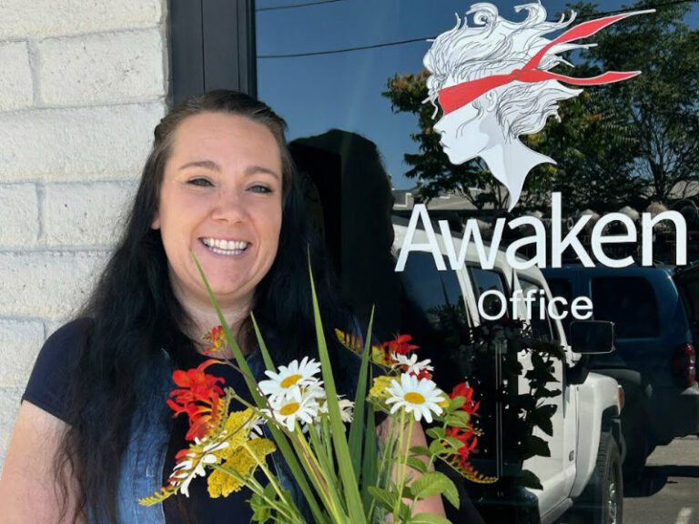 Woman standing in front of Awaken Reno Offices holding flowers